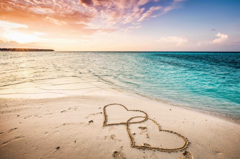 Два сердца, нарисованные на песке на пляже
